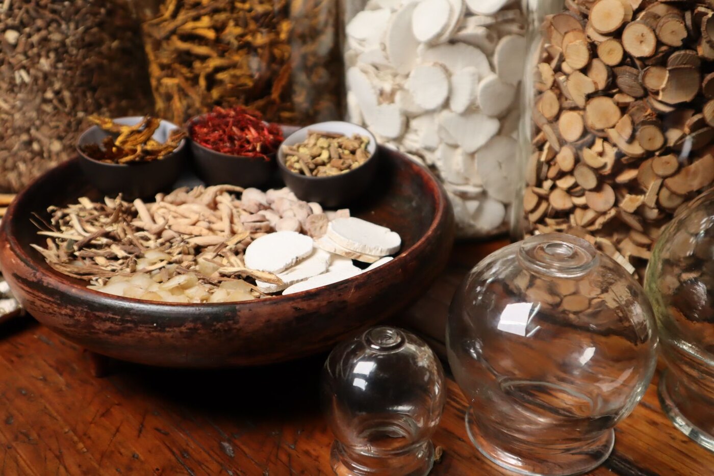 Plantas medicinales chinas y ventosas de cristal sobre una mesa de madera